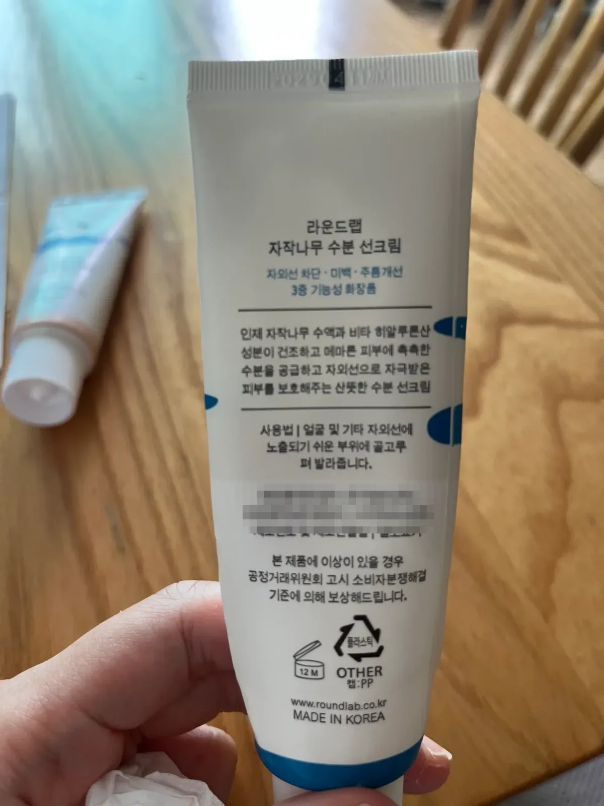 남색 선크림 튜브 뒷면의 획이 가늘고 군데군데 흐린 제품 표기 인쇄