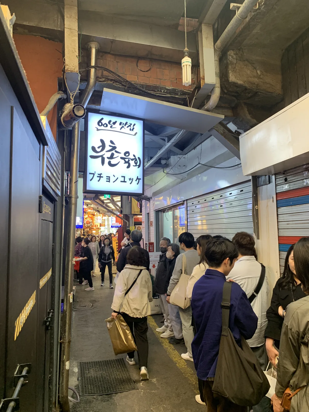 광장시장 좁은 골목길 안쪽에 자리 잡은 부촌육회 본점 입구와 대기 의자들